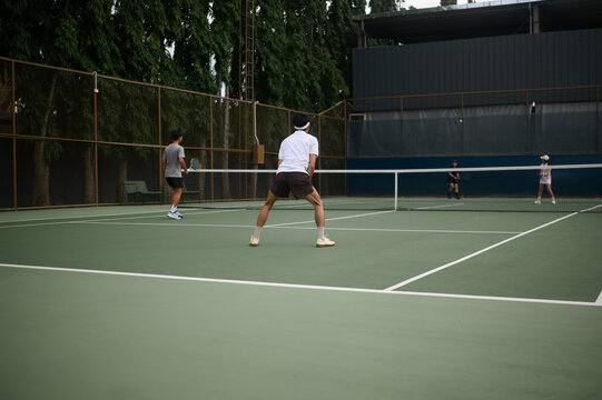 Tennis Players Competing in Doubles Match on Outdoor Green Hard Court