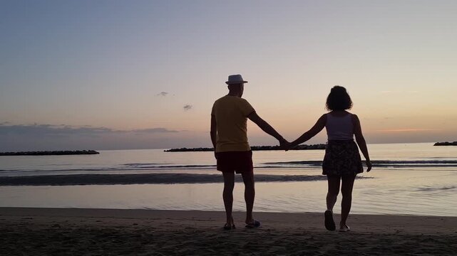 couple walking on the beach at sunset