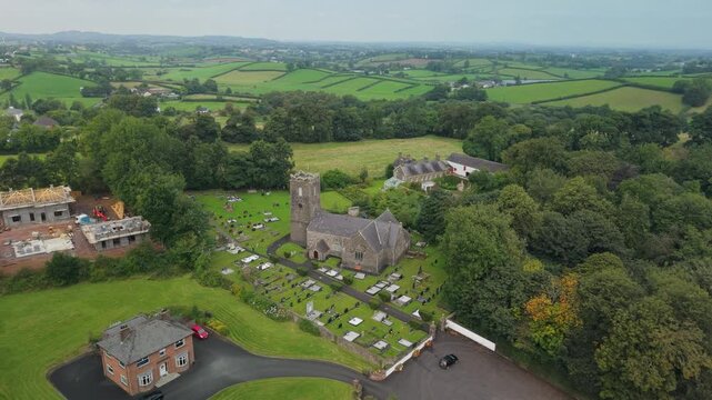 Aerial pull back from St Michael's Church of Ireland and its graveyard in Castlecaulfield to the rolling farmland of County Tyrone, Northern Ireland