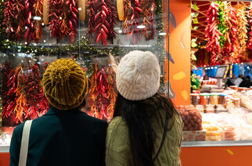 Naklejka premium People looking at market display of red peppers and dried corn, exploring local food and culture