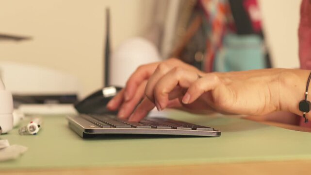 Female hands typing on a wireless computer keyboard at a desk