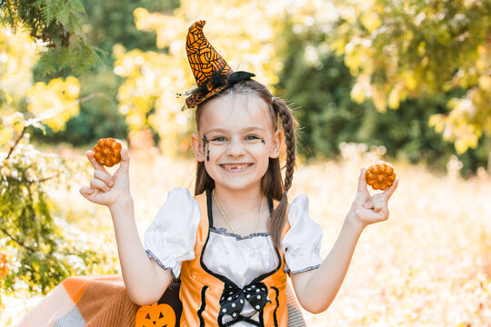 Girl Dressed for Halloween Holds Pumpkin Treats in a Forest During Autumn in October