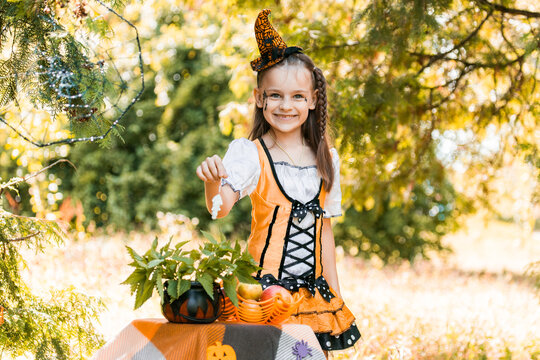 Girl Wearing a Costume With a Pumpkin Decorates for Halloween During Autumn With a Smile in October