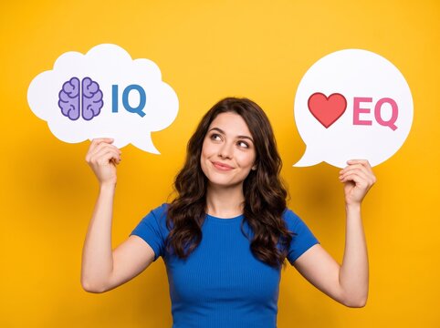 Thoughtful young woman holding IQ brain speech bubble and EQ heart speech bubble while choosing between logic and emotion on a vibrant yellow studio background in a mental balance concept idea