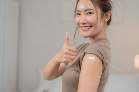 Vaccination, immunization and healthcare concept. Smiling young Asian woman shows a bandage on her upper arm after receiving a vaccine. Vaccination, vaccine, immunity, healthcare	