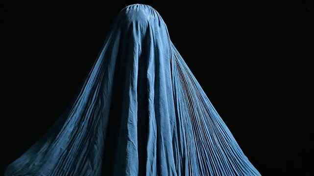 Woman wearing a traditional blue burqa standing against a dark background, symbolizing culture, identity, and the complex layers of tradition and privacy. Afghan culture, burqa