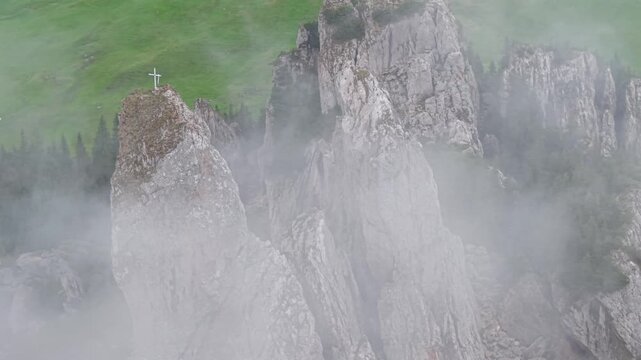 Mystical aerial view of the Pietrele Doamnei limestone formation. The Rarau Mountains landmark emerges from thick fog in Bucovina, Romania
