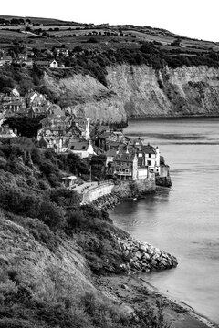 Black and white view of historic Robin Hood&rsquo;s Bay with traditional cottages, steep cliffs and calm North Sea waters in the early morning, North Yorkshire, England.