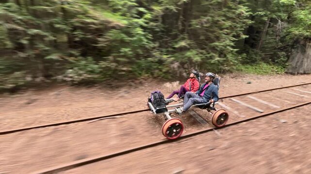 Mature couple enjoys an electric railbike journey along old railroad tracks through redwood trees and bridges in Fort Bragg California