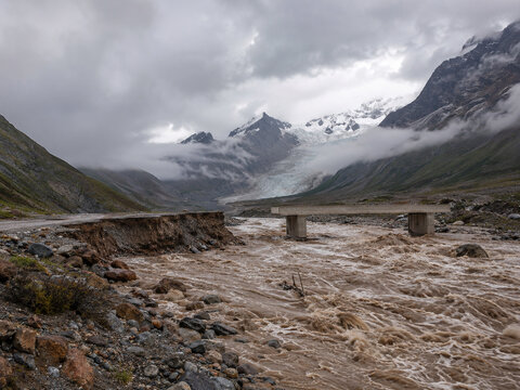 Conceptual glacial flash flood in remote Himalayan valley with damaged bridge