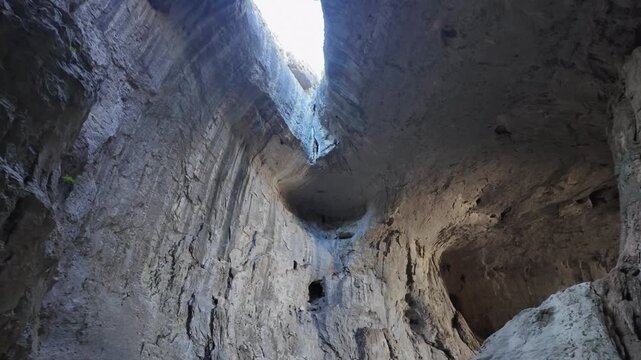 Majestic view from inside Prohodna Cave in Bulgaria, looking up at the famous rock formation known as the Eyes of God, a natural wonder