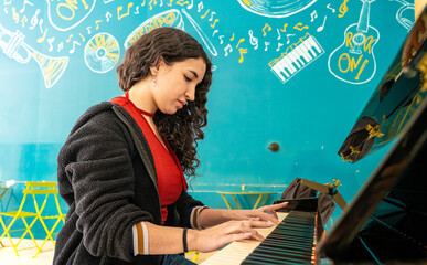 Young woman playing piano concentrating on music performance © Fabian Vargas