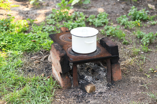 Homemade outdoor brick stove with a cooking pot in the yard.