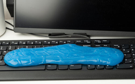 Bright blue slime sits on a keyboard in an office setting