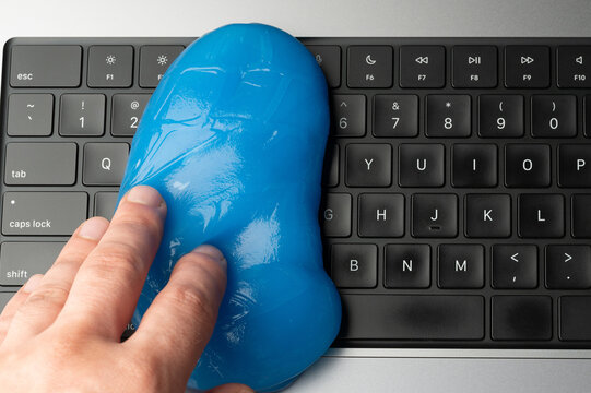 Cleaning a keyboard with blue cleaning gel and a hand