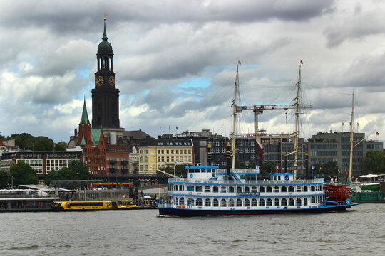 Hamburg, Germany - August 7, 2026: Hamburg harbor waterfront with Louisiana Star paddlewheel boat and St Michaelis church tower
