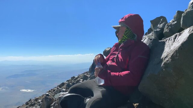 Hiker drinks water during rest stop in side view on Mount Ararat above 4000 meters, showing high-altitude trekking, endurance, hydration, and adventure tourism on a demanding ascent