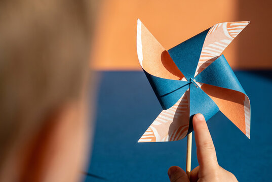 Paper pinwheel in a child hand with colorful playful background