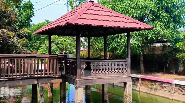 Tilt up shot of wooden gazebo pavilion over green water pond
