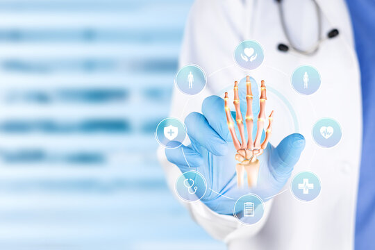 Especialista m&eacute;dico examinando un gr&aacute;fico de huesos de la mano humana para el diagn&oacute;stico de fracturas, ortopedia y concepto de salud. Aislado sobre fondo bokeh azul.