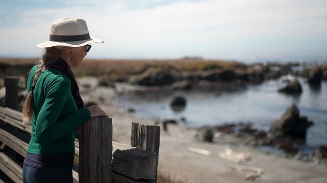 Mature woman explores the boardwalk at Mac Kerricher State Park while enjoying the clear day next to the ocean in Fort Bragg.