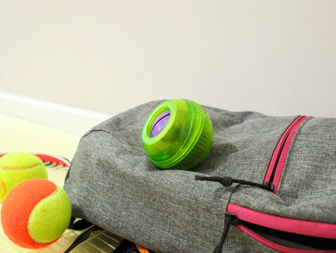 Gyroscopic wrist trainer Powerball next to a tennis racket and tennis balls. Sports equipment for grip strength, wrists, and forearms, suitable for tennis training