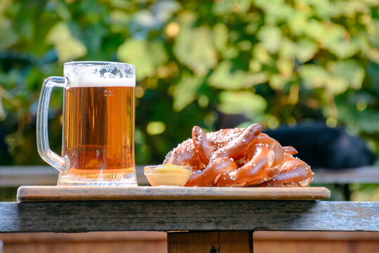 beer and pretzel on a wooden plank. outdoor scenery. oktoberfest holiday design background