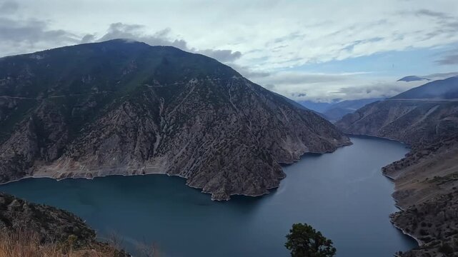 Coruh River winds through a wide mountain canyon view in northeastern Turkey, showing steep rocky slopes, reservoir-like water, regional geography, scenic travel, dramatic highland landscape tourism
