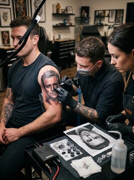 Professional Tattoo Artist Inking Realistic Portrait on Man's Arm