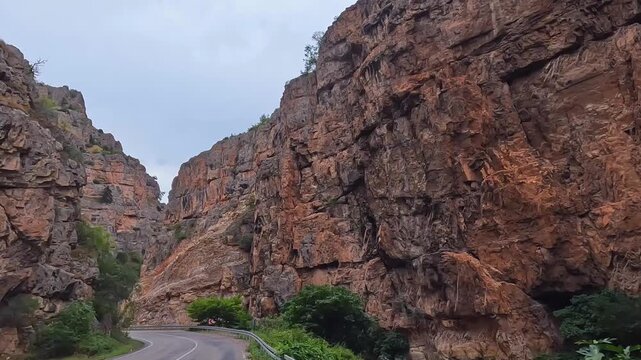 Mountain road winds in wide view through a dramatic rocky gorge in Turkey, showing scenic overland travel, exposed geology, rural infrastructure, road engineering, and destination tourism