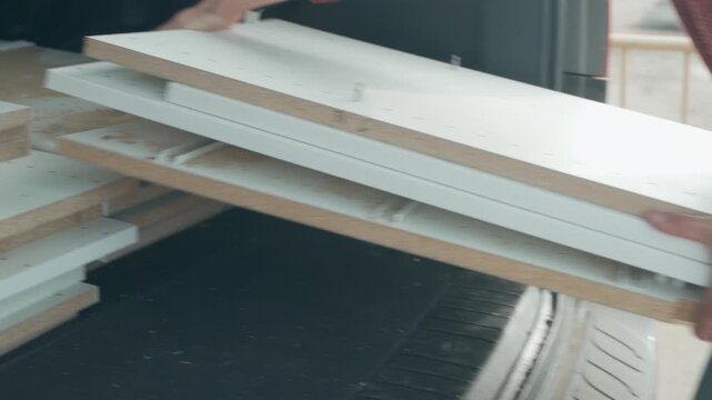 Woman unloading old wooden furniture panels from SUV at recycling depot