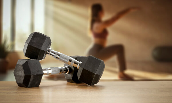 Dumbbells on wooden bench with blurred gym interior &ndash; fitness and strength training concept