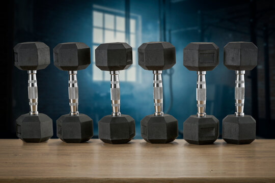 Dumbbells on wooden bench with blurred gym interior &ndash; fitness and strength training concept