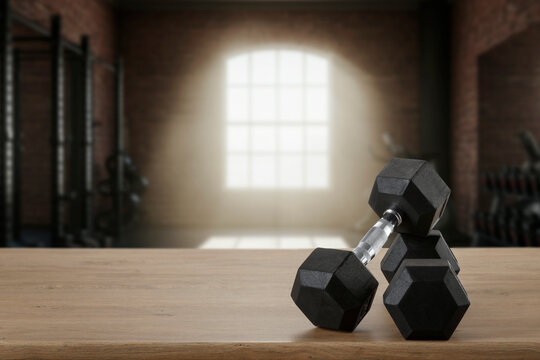 Dumbbells on wooden bench with blurred gym interior &ndash; fitness and strength training concept