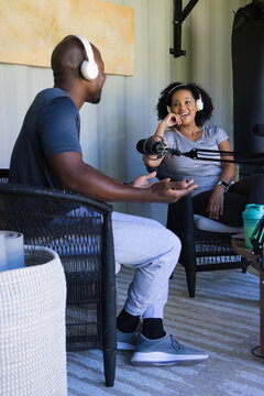 Diverse podcast hosts recording chat in metal studio wearing headphones and using microphone