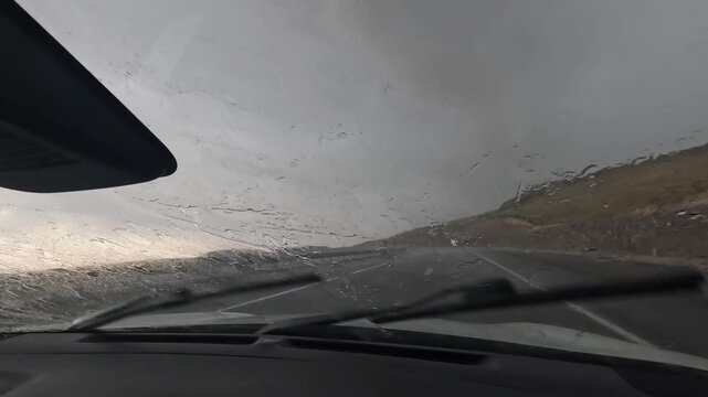 Car driving through heavy rain in dashboard view on a rural highway in Turkey, showing reduced visibility, windshield wipers, storm conditions, road safety, wet weather travel, and hazardous driving