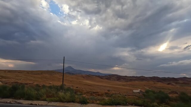 Turkish countryside unfolds in wide view under dramatic storm clouds, showing rural road travel for tourism promotion, destination marketing, transport planning, and changing weather context