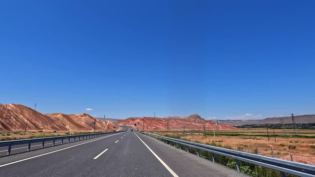 Highway drive through red mountains in wide road-level view, crossing arid Turkey landscape for travel, transport, road trip, logistics, destination marketing, and regional tourism promotion