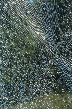 Cracked shattered glass surface with radial fracture pattern and reflections