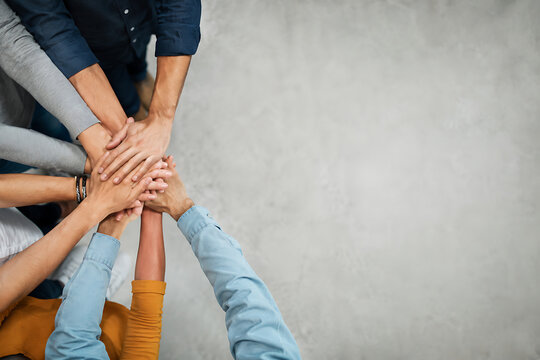 A group of hands stacked together demonstrates collaboration and unity on a gray surface teamwork togetherness cooperation partnership support community connection collective people assistance helping