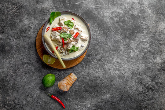 Thai chicken mushroom coconut milk soup tom kha gai in gray bowl with thai spices. Top view