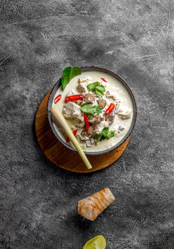 Thai chicken mushroom coconut milk soup tom kha gai in gray bowl with thai spices. Top view