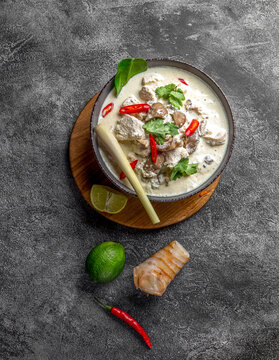Thai chicken mushroom coconut milk soup tom kha gai in gray bowl with thai spices. Top view
