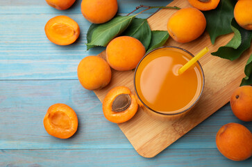 Apricot juice in glass, fresh fruits and leaves on light blue wooden table, flat lay © New Africa