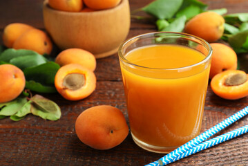 Apricot juice in glass, fresh fruits and drinking straws on wooden table, closeup © New Africa