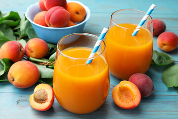 Apricot juice in glasses, fresh fruits and leaves on light blue wooden table, closeup © New Africa