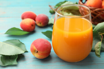 Apricot juice in glass, fresh fruits and leaves on light blue wooden table, closeup © New Africa
