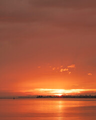 Obraz premium Orange sun dips low, painting sky and water in warm hues