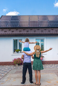 A family looks at solar panels on the roof of a house. Selective focus.
