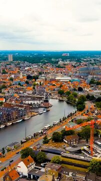 Vertical video. Haarlem, Netherlands. Windmill De Adriaan (1779). Windmill from the 18th century. Panoramic view of Haarlem city center. Cloudy weather during the day. Summer. Drone footage. Rich col